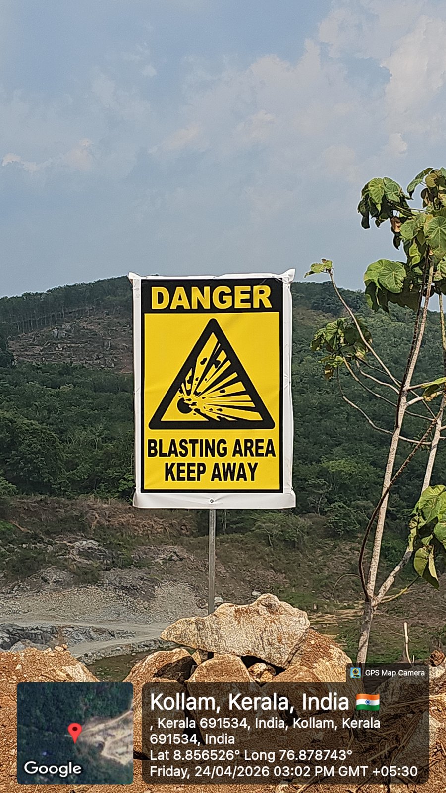 Yellow danger controlled blasting area sign with granite bedrock slopes behind